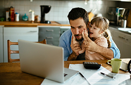 Father and daughter at a laptop in the kitchen